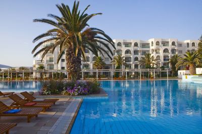 Sun loungers and palm tree beside the pool at El Mouradi Mahdia