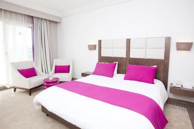 Double room with pink cushions and bed runner at El Mouradi Hammamet