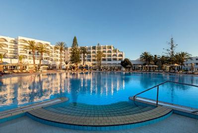 Large outdoor swimming pool with the hotel behind at El Mouradi Palace Large outdoor swimming pool with the hotel behind at El Mouradi Palace